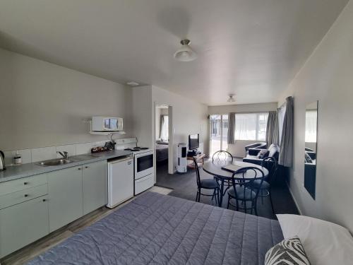 a kitchen and living room with a table and chairs at ASURE Gables Motor Lodge in Greymouth