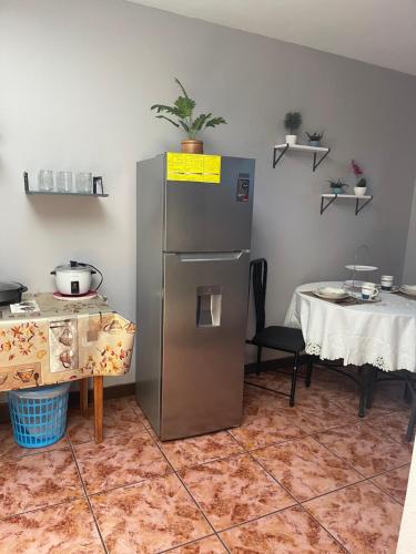 a kitchen with a stainless steel refrigerator and a table at Relax In Downtown Alajuela 5 min Near The Airport in Alajuela