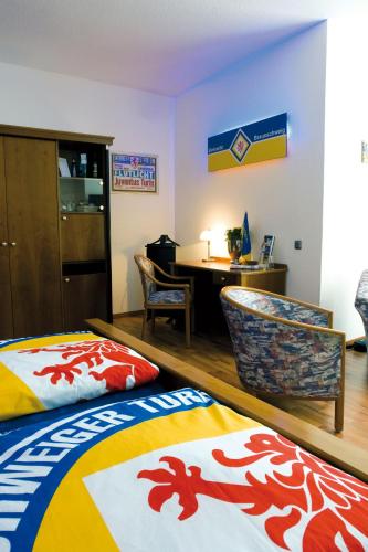 a room with two beds and a desk and a table at Hotel Deutsches Haus in Braunschweig