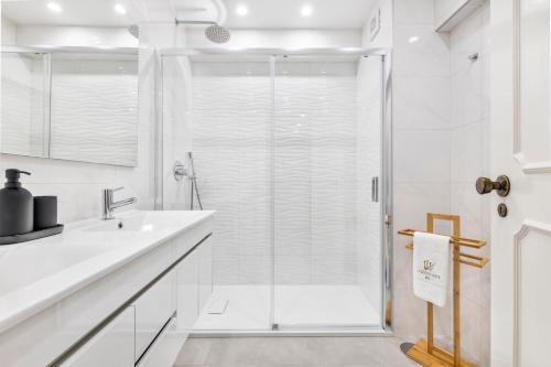 uma casa de banho branca com um chuveiro e um lavatório. em Faro Main Avenue Apartment em Faro