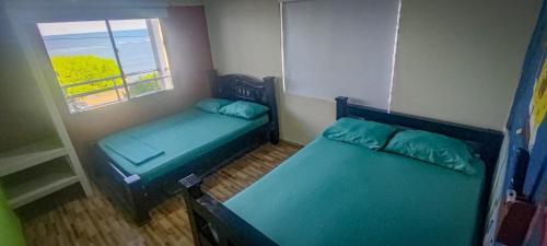 two beds in a small room with a window at Hostal mis dos ángeles in Santiago