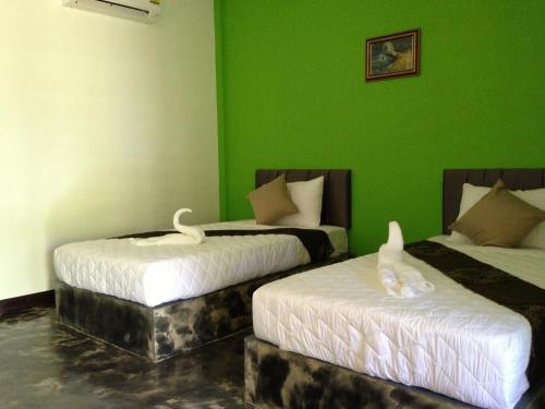 two beds in a green room with swans on them at Baan Rai Phufah Resort Chiangrai in Ban Pa Ruak
