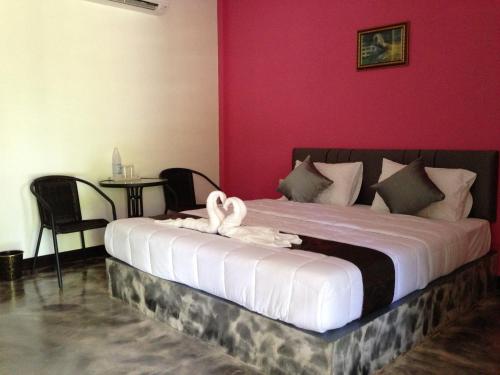 a bedroom with a large bed with pink walls at Baan Rai Phufah Resort Chiangrai in Ban Pa Ruak