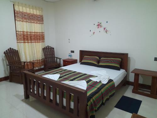 a bedroom with a wooden bed with two chairs at Sigiri Jungle Villa in Sigiriya