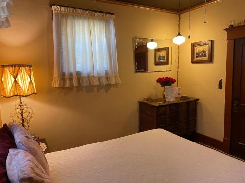 a bedroom with a bed and a dresser and a window at 1912 Nostalgic TrainCrew Boarding House in Potter