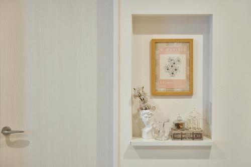 une étagère blanche avec des vases et une photo sur un mur dans l'établissement The Bird Tennoji, à Osaka
