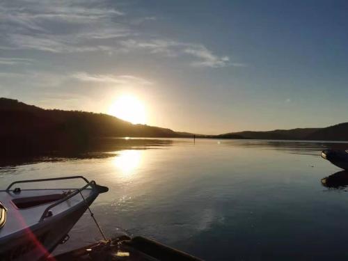 a boat on a lake with the sun in the background at Your Perfect Waterfront Escape in Bar Point