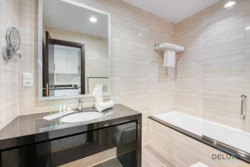 a bathroom with a sink and a tub and a mirror at Luxurious studio fully furnished 5 stars hotel facilities in Dubai South in Dubai