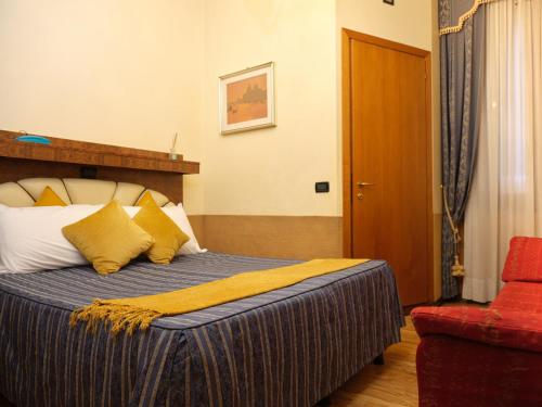 a hotel room with a bed and a red chair at Atlantide Hotel in Venice