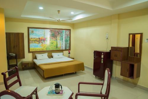a bedroom with a bed and a table and chairs at Hotel Chanma International in Coimbatore