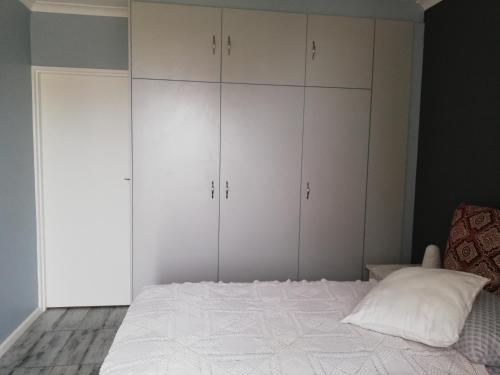 a bedroom with white cabinets and a bed with a pillow at Nagua bay in Gordonʼs Bay