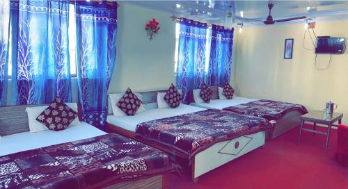 two beds in a room with blue curtains at Hotel Young Mamta in Srinagar