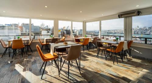 un restaurante con mesas, sillas y ventanas grandes en Sayeban Gold Hotel, en Estambul