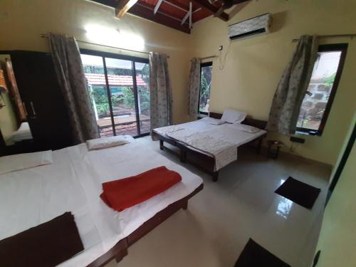Cette chambre comprend 2 lits, une table et une fenêtre. dans l'établissement Triskelion - Bed and Breakfast, Family home stay by Joshi Brothers, à Dapoli