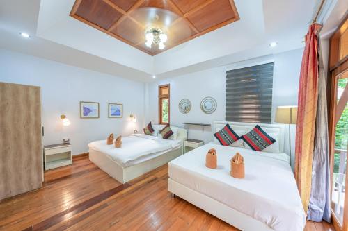 two beds in a room with wood floors at Bali Beach Pool Villa in Pattaya South