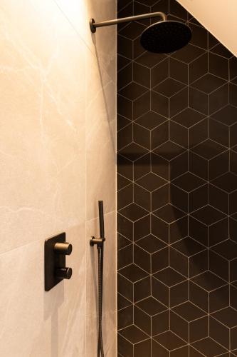 a bathroom with a shower with a black tiled wall at Boutiquehotel Princenjagt in Middelburg