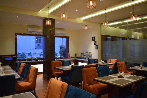 a restaurant with tables and chairs and a large window at Hotel Ambica Katra in Katra