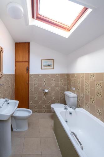 a bathroom with a tub and a toilet and a skylight at Sea Poppies in Thorpeness