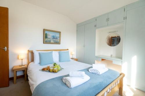 a bedroom with a large bed with two towels and fruit on it at Sea Poppies in Thorpeness