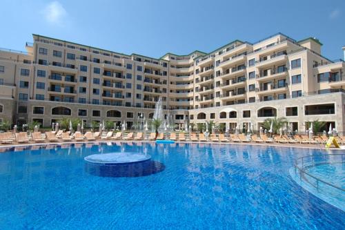 een groot zwembad met stoelen en een groot gebouw bij Luxury Apartment Zlatna Kotva in Goudstrand