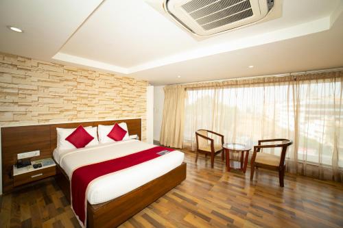 a bedroom with a bed and a table with chairs at Icon Business Hotel by Bhagini in Bangalore