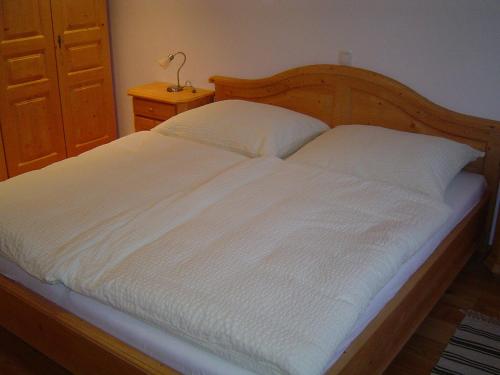 a bed with white sheets and a wooden headboard at Kalßnhof in Bad Aussee