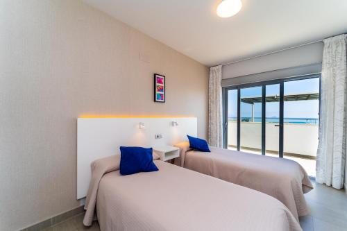 two beds in a room with a view of the ocean at Vistamar Luxury Apartments By DLV -Adults Only- in Villajoyosa