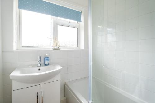 a white bathroom with a sink and a window at 54 Linden Road in Aldeburgh