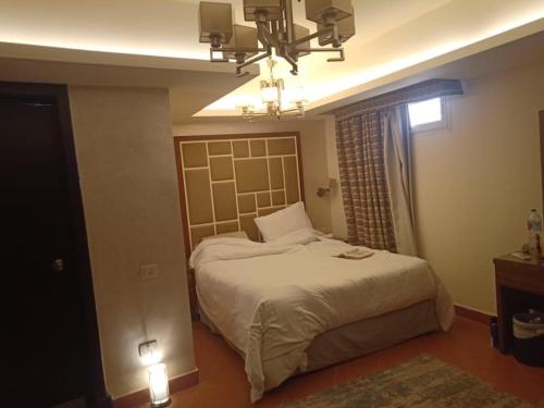 a bedroom with a bed and a chandelier at Amazing sea view Penthouse Apartment in Pyramids Porto El-Sokhna in Ain Sokhna