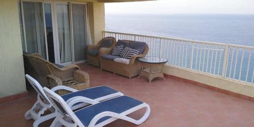 a balcony with chairs and a table and the ocean at Amazing sea view Penthouse Apartment in Pyramids Porto El-Sokhna in Ain Sokhna