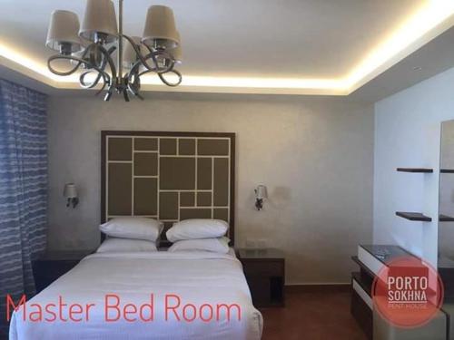 a bedroom with a large bed and a chandelier at Amazing sea view Penthouse Apartment in Pyramids Porto El-Sokhna in Ain Sokhna