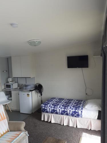 a bedroom with a bed and a tv on the wall at Paeroa Rail Trail Motel in Paeroa