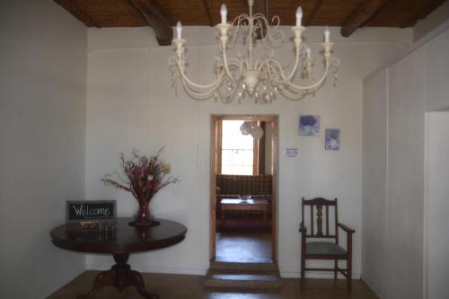 a chandelier in a room with a table and a chair at The Lemon Tree in Prince Albert
