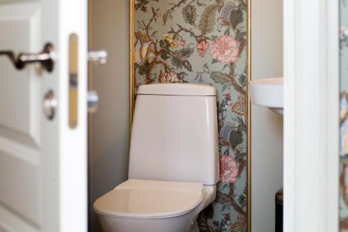 a bathroom with a toilet with a floral wallpaper at Strandvillan Hotell och Bed & Breakfast in Lysekil