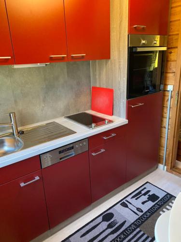 una cocina con armarios rojos y una silla roja. en Huck’s Ferienhäuser, en Borstel