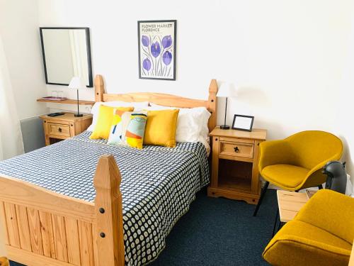 a bedroom with a bed with yellow pillows and a chair at La Maison du Canal in Rostrenen