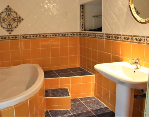 ein orangefarbenes gefliestes Badezimmer mit einem Waschbecken und einer Badewanne in der Unterkunft Orangerie LAGAILLARDE in Thil