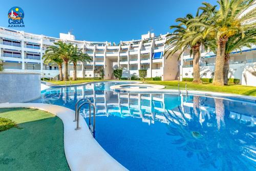 a large swimming pool with palm trees in front of a building at Apartamentos Nova Romana Casa Azahar in Alcossebre