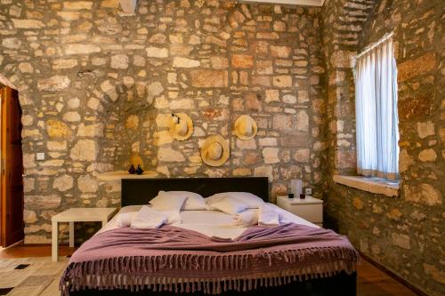 a bedroom with a bed with a stone wall at annemin harabesi otel in Çeşme