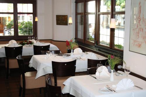 a restaurant with white tables and chairs and windows at Die Krone in Staufen im Breisgau