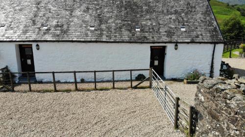 a white barn with a fence in front of it at Garrison Farm with Hot Tub in Inversnaid
