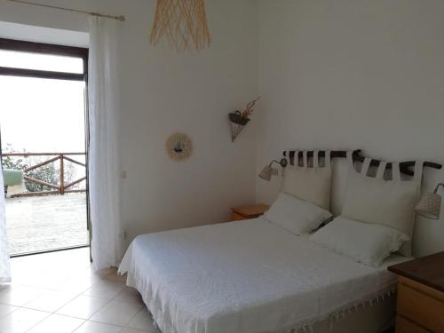 a white bedroom with a bed and a large window at Casa Afrodite in Praiano