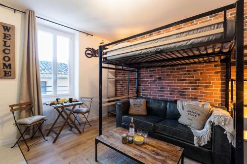 un salon avec un canapé et un mur de briques dans l'établissement Bricks Industry Hyper Centre Fontaine Moussue, à Salon-de-Provence