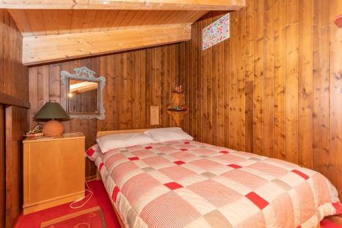 a bedroom with a bed in a room with wooden walls at Condominio Pien dal Lat in Selva di Cadore