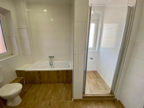een badkamer met een bad, een toilet en een douche bij Pension Kaufungen in Kaufungen