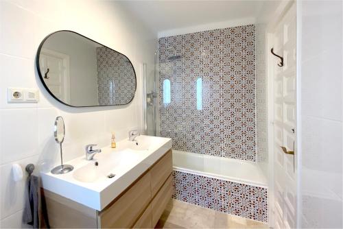 een witte badkamer met een wastafel en een spiegel bij Casa Lena Town House with private garden near the beach in Nerja