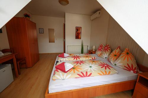 a bedroom with a bed with colorful sheets and pillows at Nádasdi Ház in Szekszárd