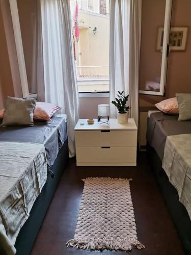 a room with two beds and a window and a rug at Santi Padri Apartment in Corfu