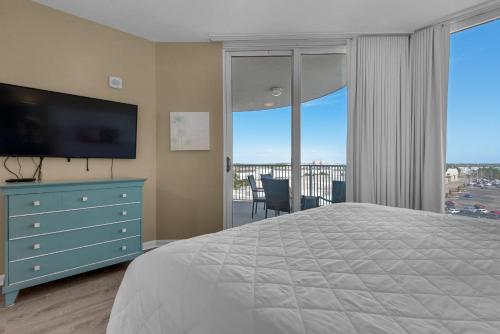 a bedroom with a bed and a television and a balcony at Palms Resort #1614 Jr. 2BR in Destin