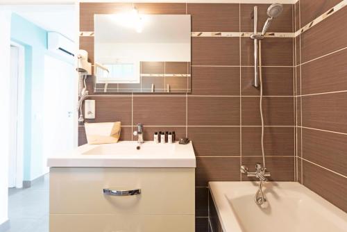een badkamer met een wastafel, een bad en een spiegel bij SELECT'SO HOME - Résidence La Fossette - Prestations de qualité & Services Hôteliers - FOS-02 in Le Lavandou